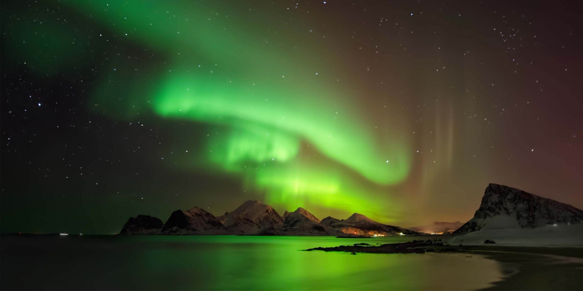 Aurora borealis über der verschneiten Insel Vestvégéya, Lofoten